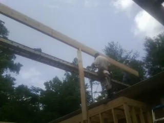 Carpenter setting a ridge beam over a new addition frame — Ice Dam Removal by Roofing Brothers in Zebulon