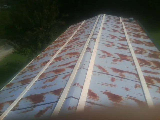 Rusted metal roof panels with new wood purlins before replacement — Storm Damage Roof Repair in Zebulon by Roofing Brothers