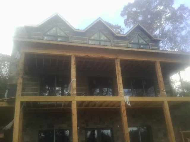 Dormers and porch framing on a large log home under construction — Roof Coating work by our crew in Zebulon