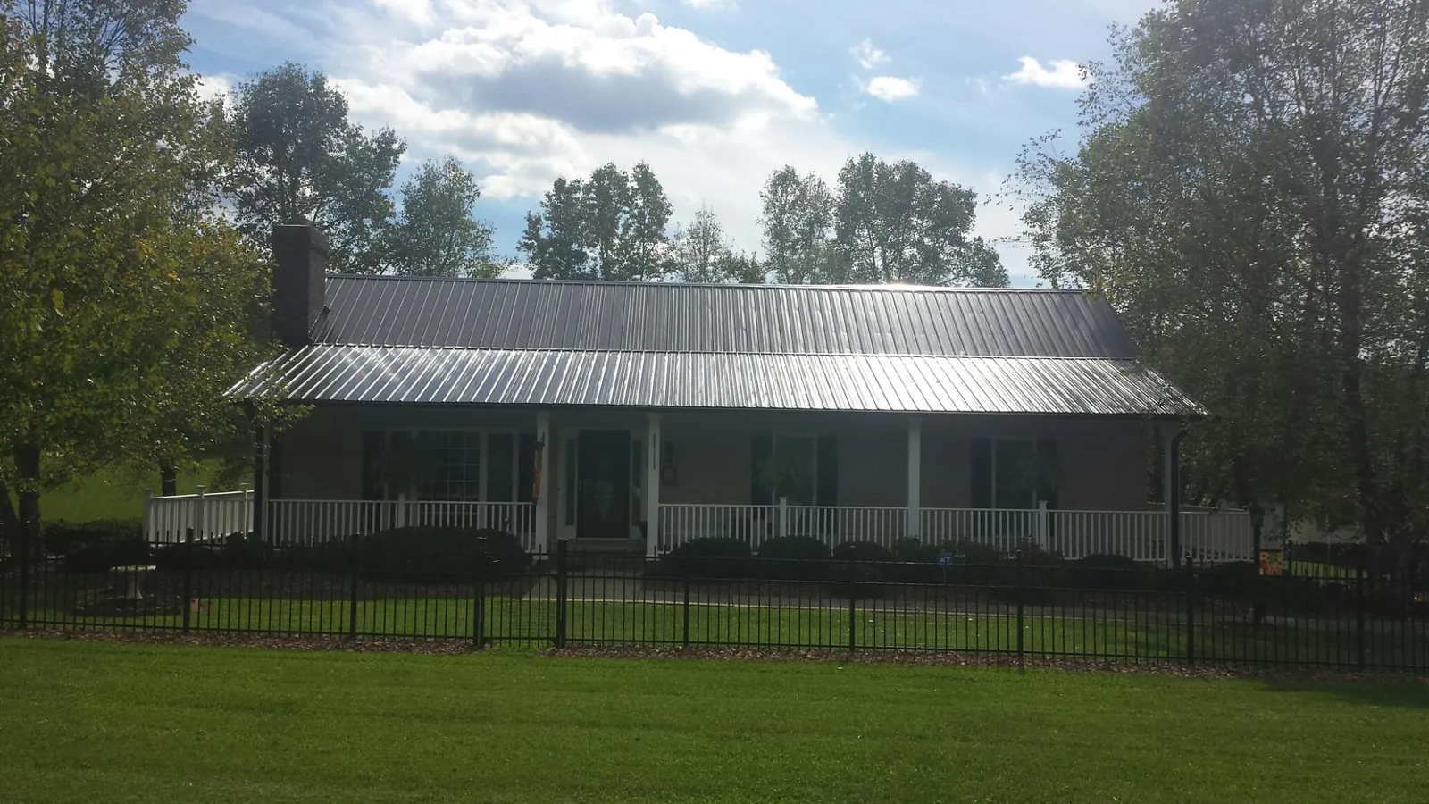 Gray metal roof on a brick ranch with a full width front porch — Gutter Guard Installation work by our crew in Zebulon