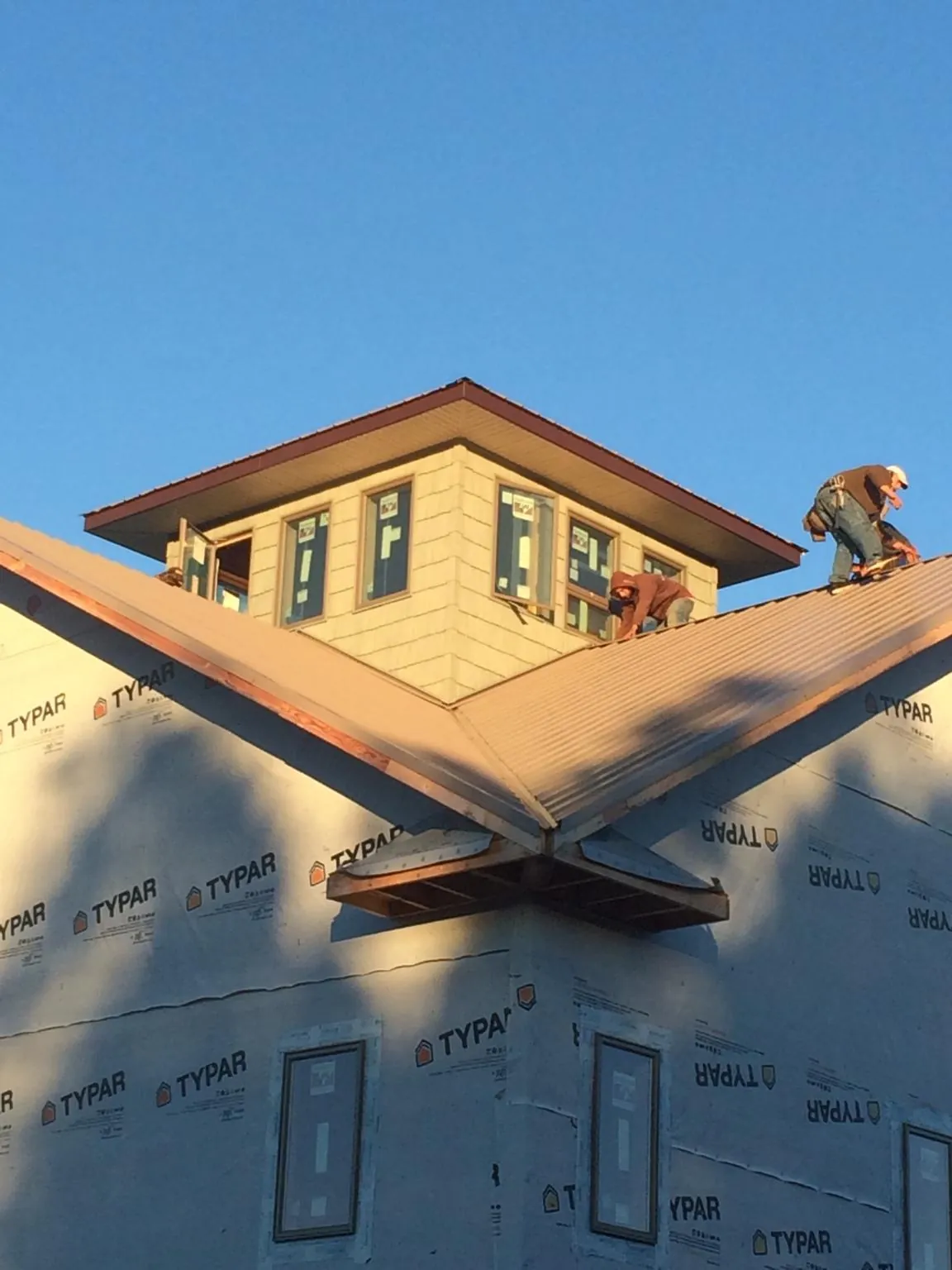 Roofers working around a rooftop cupola on a new metal roof at sunset — Roof Waterproofing in Zebulon by Roofing Brothers